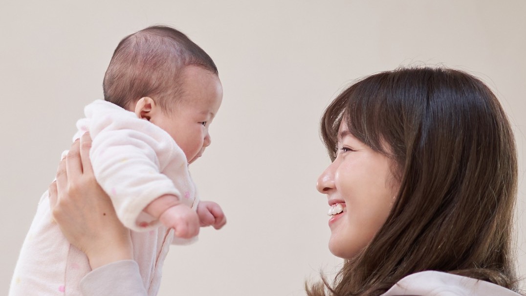 赤ちゃんを抱っこして笑顔を向き合わせるお母様